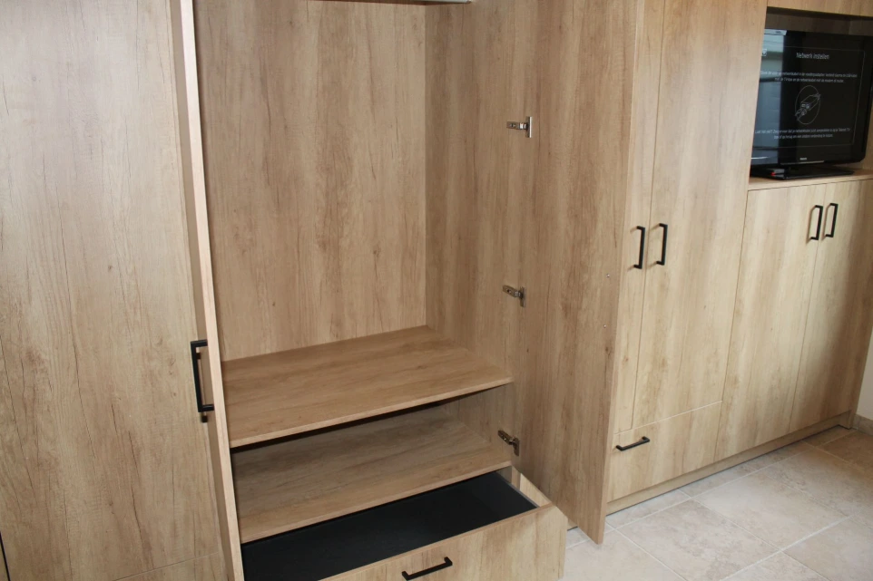 Open dressingkast op maat met lades en praktische indeling naast het tv-meubel