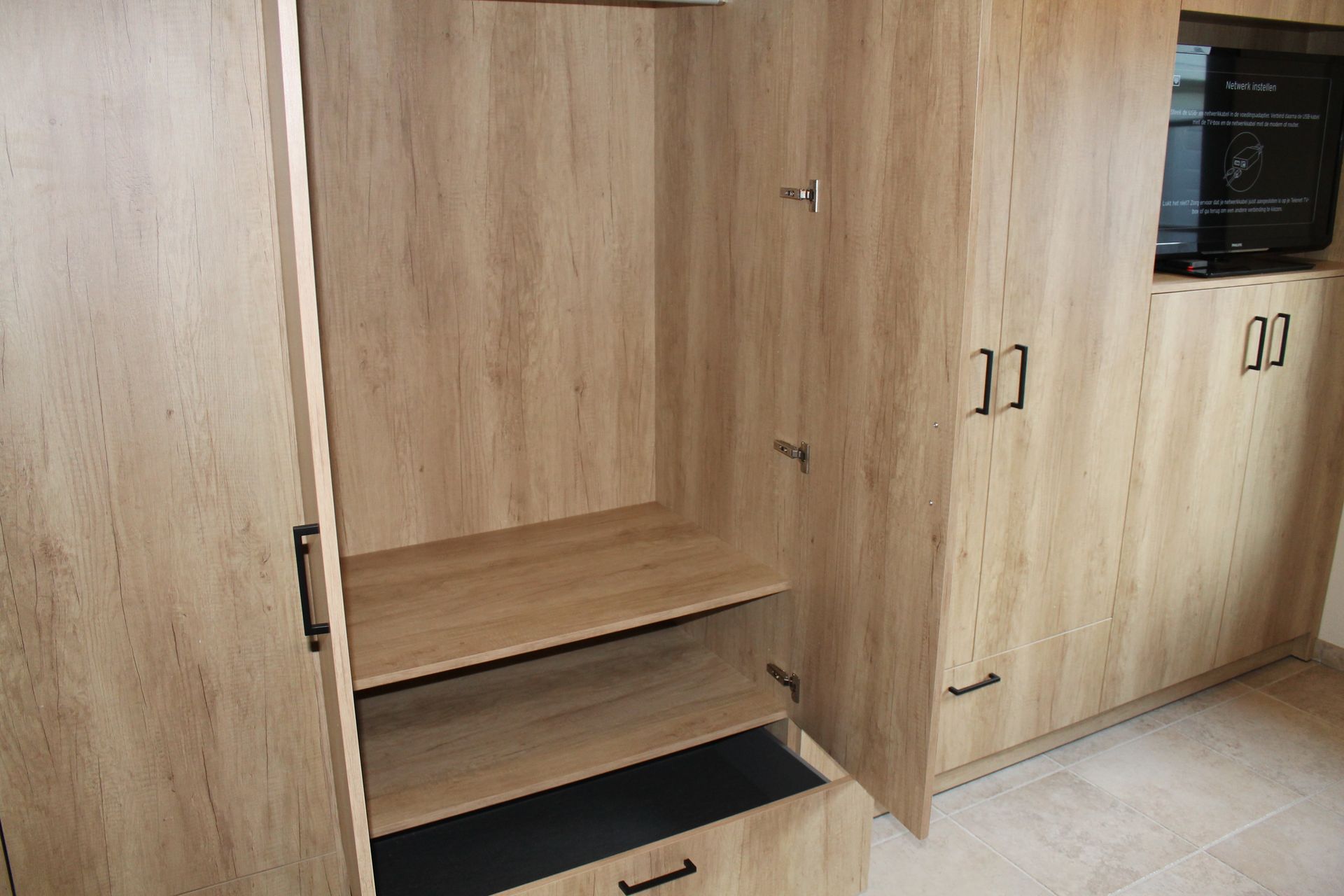 Open dressingkast op maat met lades en praktische indeling naast het tv-meubel
